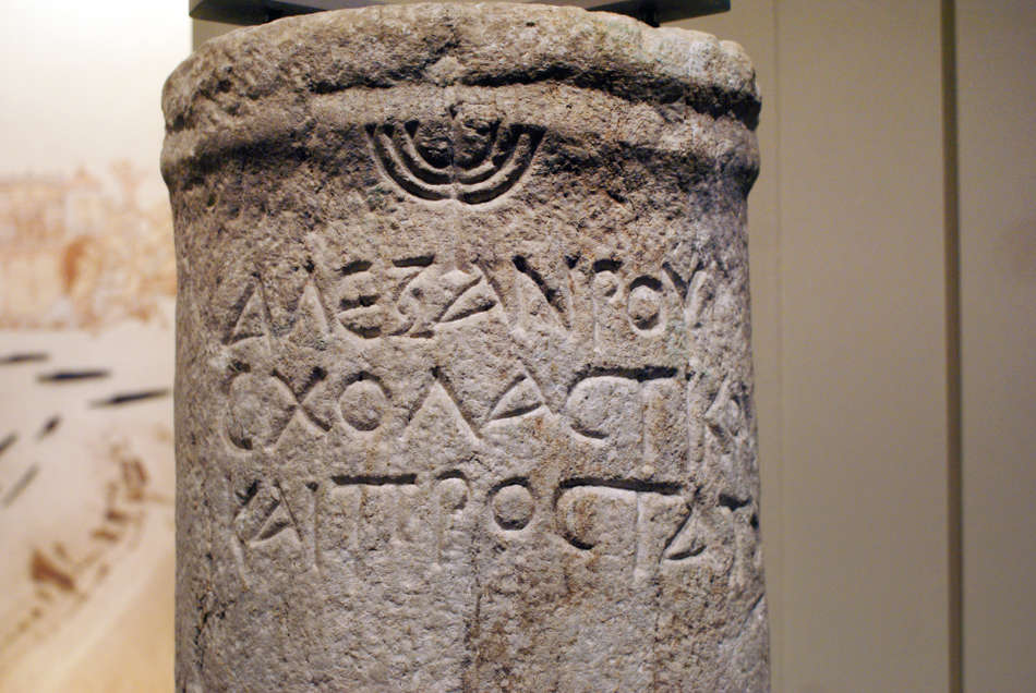 Αρχαιολογικό εύρημα - κιονίσκος - με σύμβολο της επτάφωτης λυχνίας και επιγραφή "ΑΛΕΞΑΝΔΡΟΥ ΣΧΟΛΑΣΤΙΚΟΥ ΚΑΙ ΠΡΟΣΤΑΤΟΥ"
